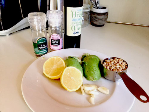 Picture of ingredients: olive oil, avocado, pine nuts, lemon, garlic, salt & pepper.